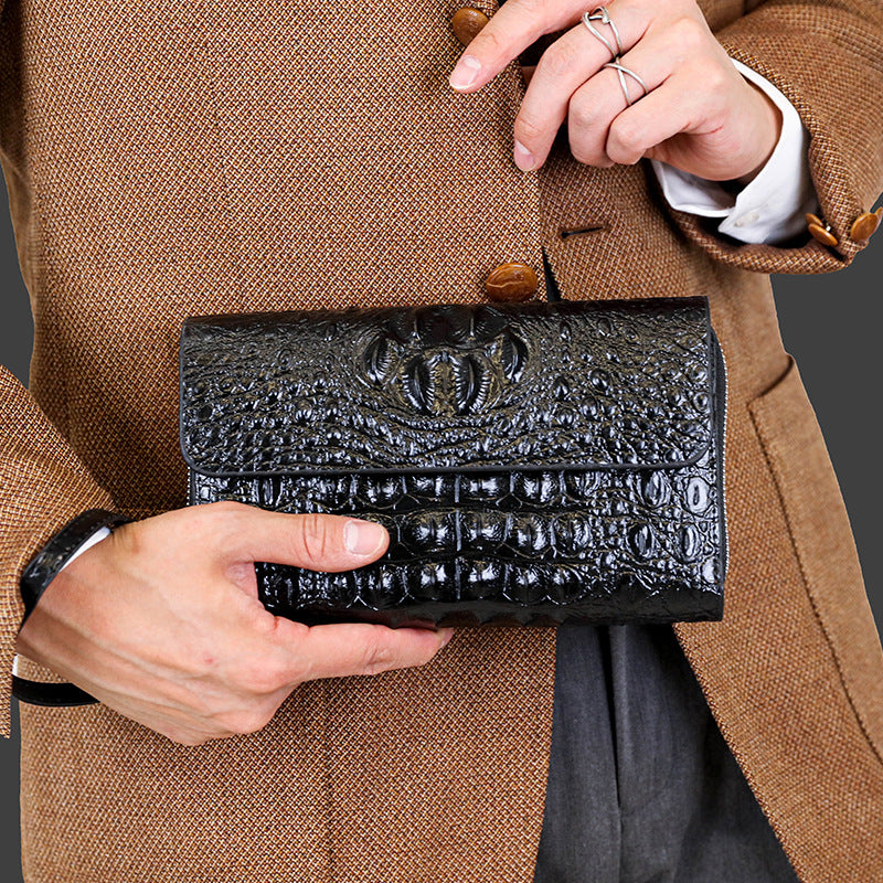 Person holding a black textured clutch against a brown coat background