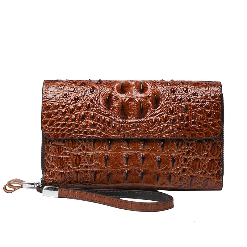 Brown crocodile-textured clutch bag with a strap on a white background