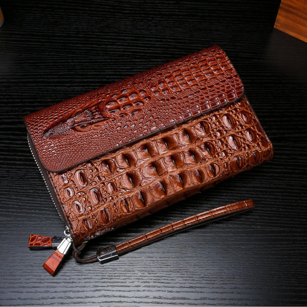 Brown crocodile-patterned clutch bag on a dark textured surface